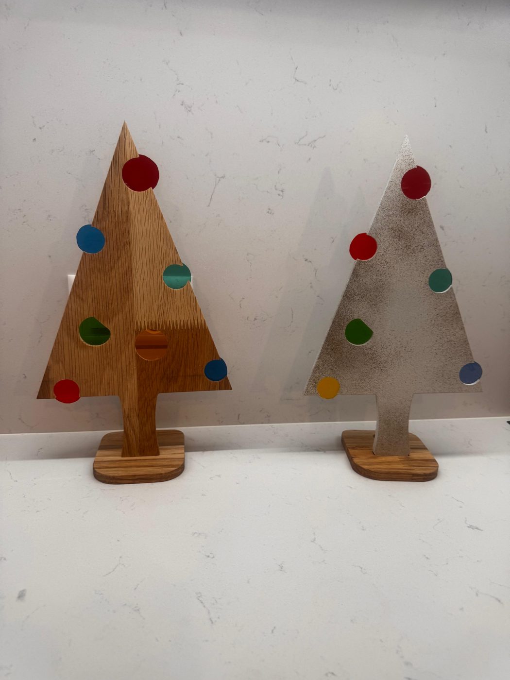 Sapins en bois décorés de boules en vitrail colorées, posés sur un socle